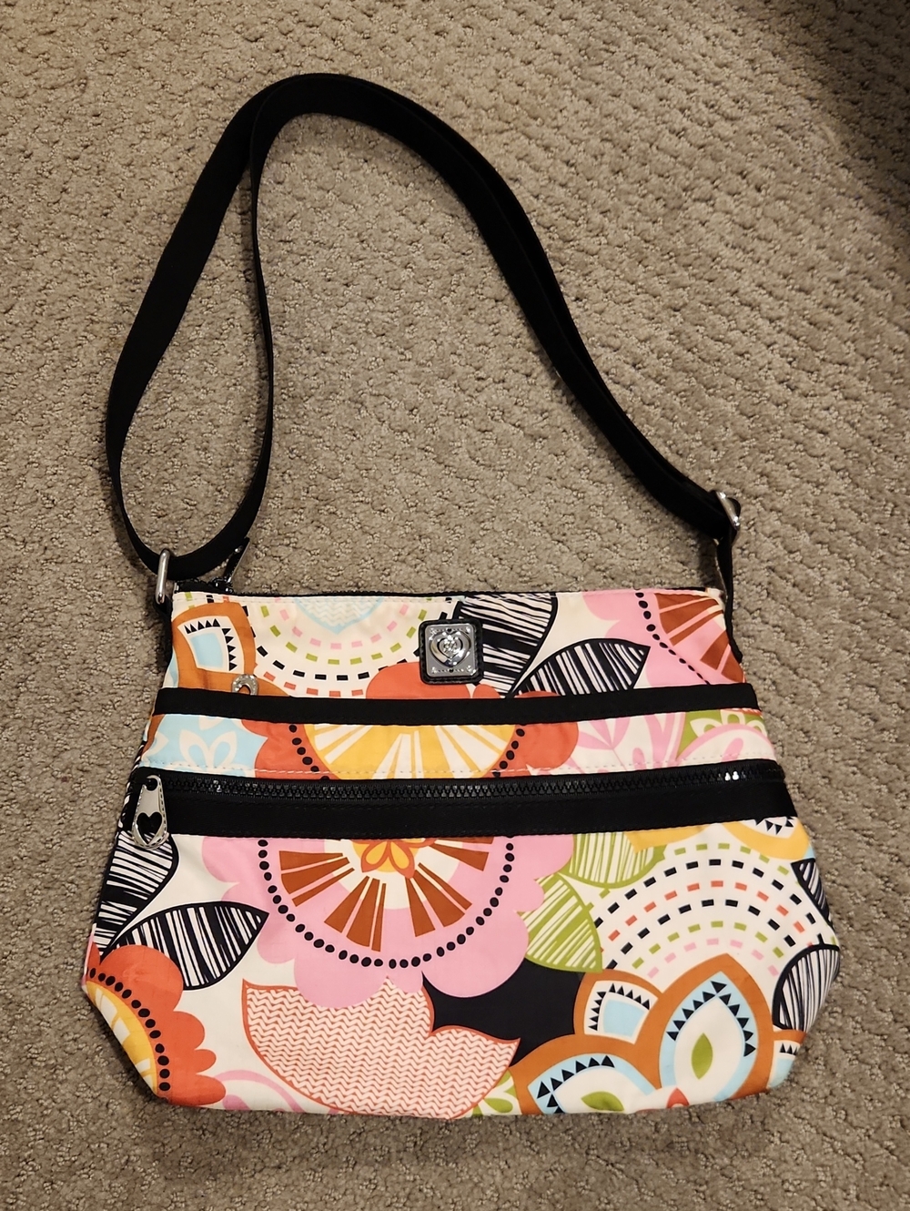 Brighton crossbody bag features a distinctive mod floral print and multiple zipp
